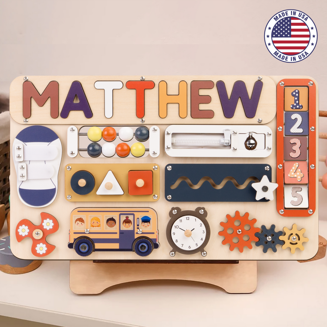A personalized Montessori busy board for toddlers, featuring rotating numbers and various sensory activities, with the name 'Madison' printed on it.